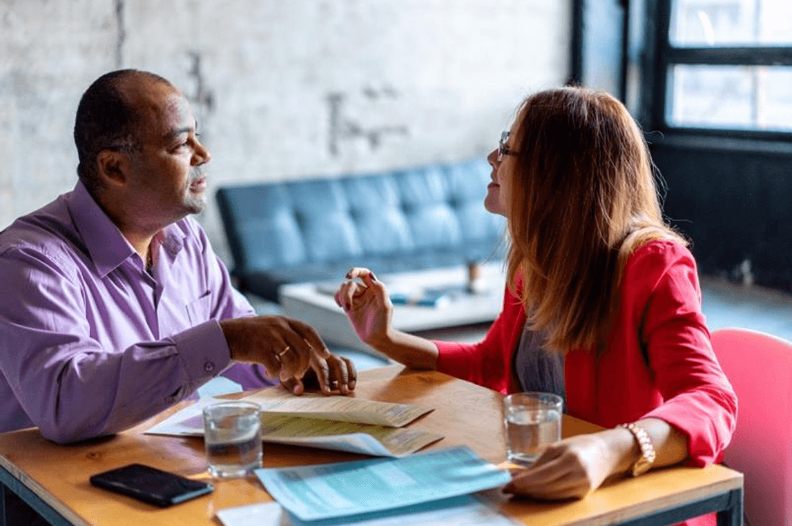 Professional discussion between two people at a table with documents